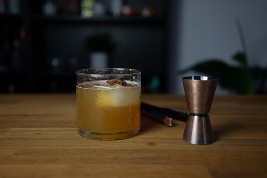 Vanilla Chai Old Fashioned Cocktail im Glas neben Cocktailzubehör